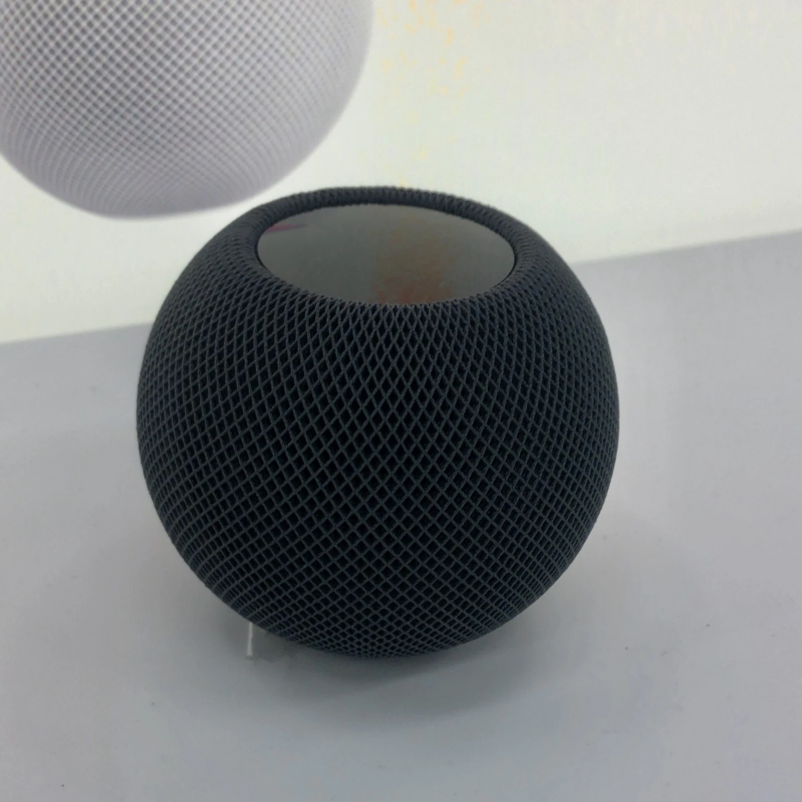 A dark original HomePod mini on display.